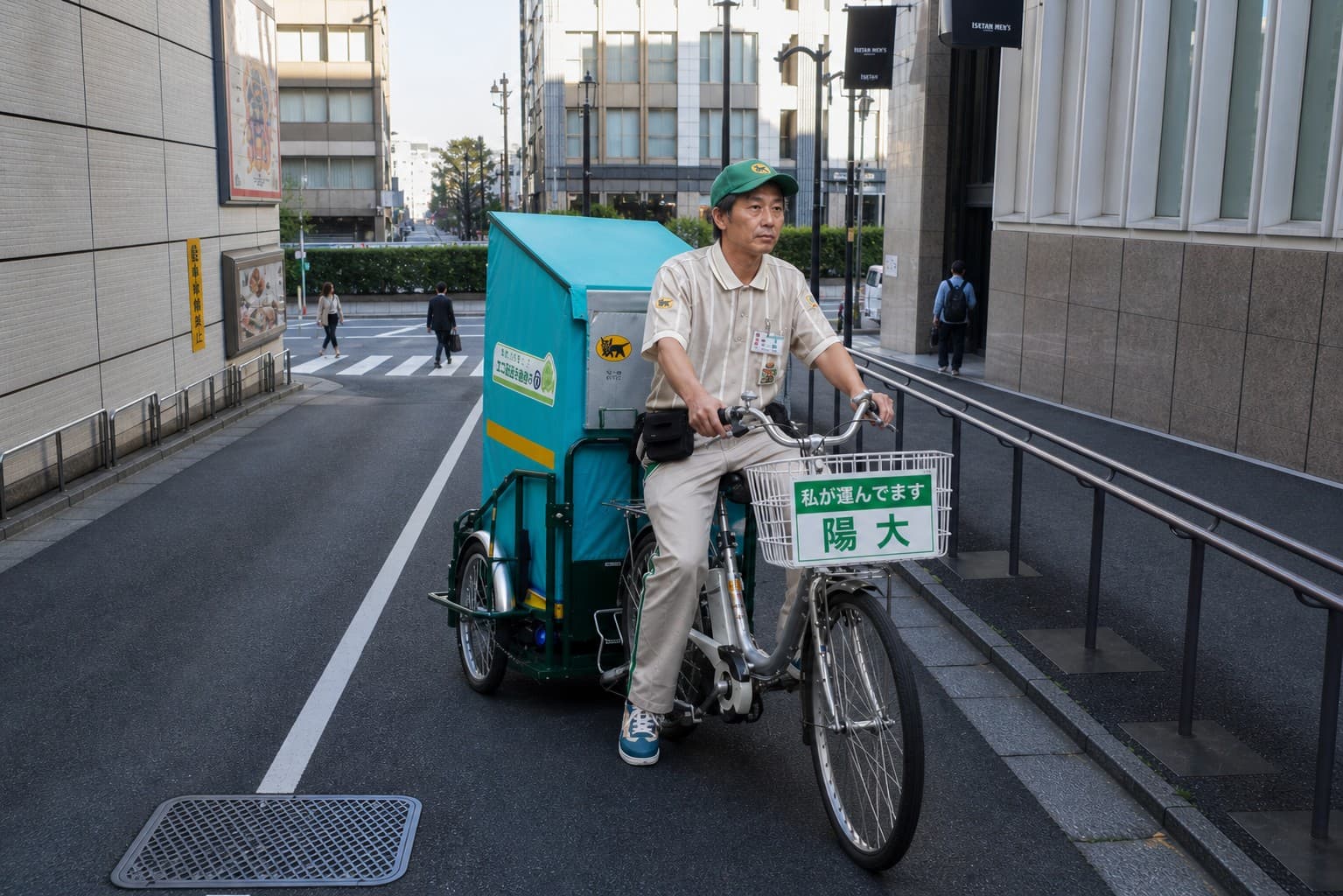 自転車のカゴに「私が運んでます 陽大」と書かれたプレートをつけて漕ぐおじさん（当時の様子を AI で再現）